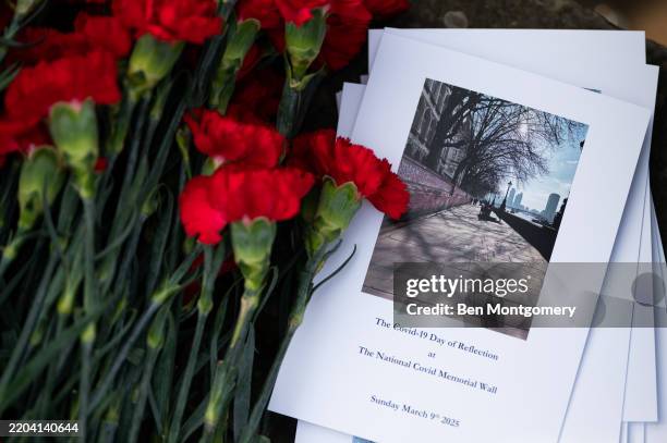 Red carnations sit alongside an order of service marking the day of remembrance at The National Covid Memorial Wall on March 09, 2025 in London,...
