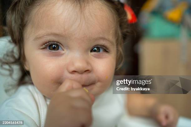 adorable bébé - âge humain souriant en mangeant - yeux bruns photos et images de collection