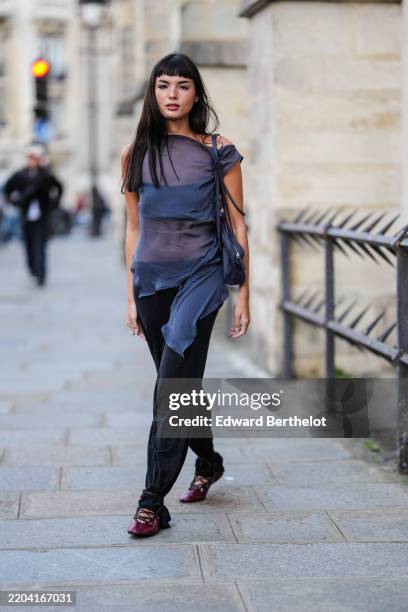 Clara Kong Vila wears short bangs long hair, dark navy blue sheer mesh sleeveless top, dark navy blue bralette top, navy blue leather bag, black...