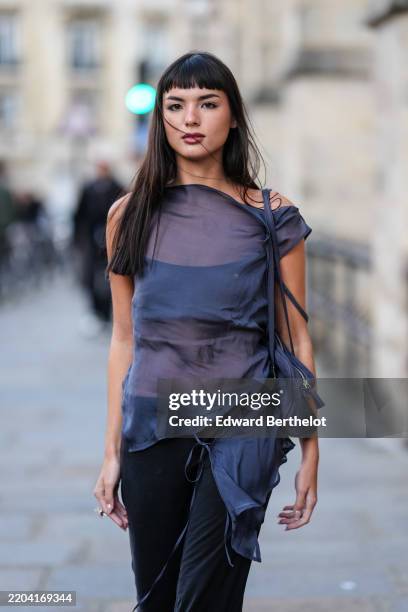 Clara Kong Vila wears short bangs long hair, dark navy blue sheer mesh sleeveless top, dark navy blue bralette top, navy blue leather bag, black...