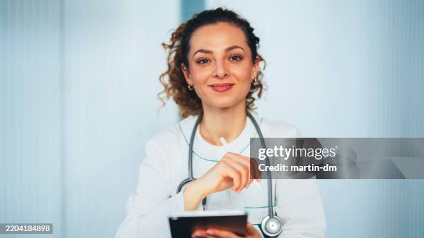 female doctor holding a digital tablet in a modern clinic - medical school stock pictures, royalty-free photos & images