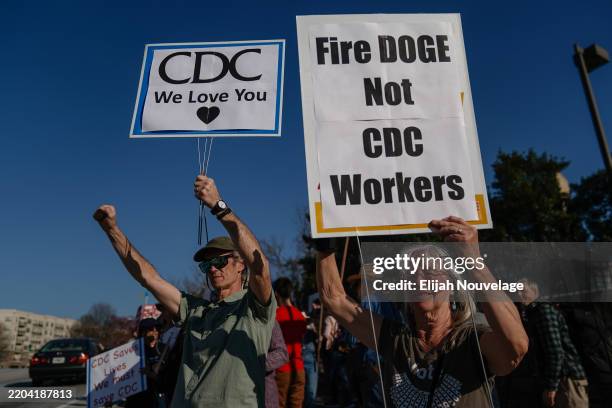 People protesting personnel cuts at the Centers for Disease Control hold signs outside the organization's main headquarters on March 12, 2025 in...
