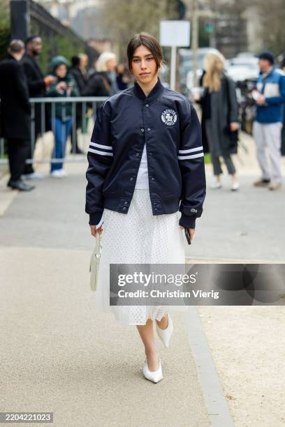 Ariadna Tapia wears blue Lacoste jacket, white pleated midi skirt, white heels, bag outside Lacoste during the Womenswear Fall/Winter 2025/2026 as...