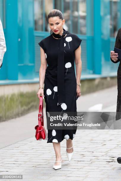 Guest wears a black and white printed midi short-sleeved dress, a red leather bag, a black scarf and white leather heeled slingback outside Akris...