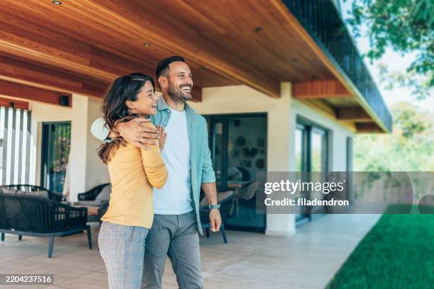 embraced couple in front of their new house - in front of stock pictures, royalty-free photos & images