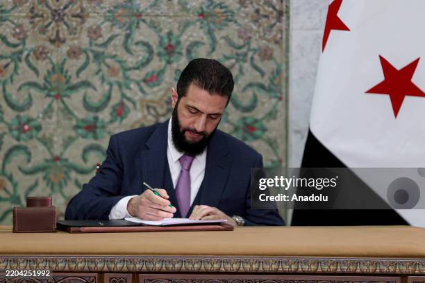 Syrian President Ahmed al-Sharaa signs a declaration outlining the main provisions of the interim constitution in a ceremony held at the People's...