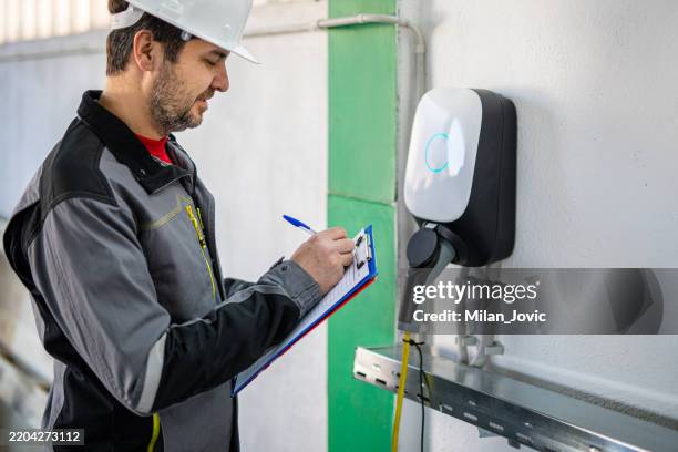 ingénieur examinant une station de recharge de voiture électrique - chargeur de batterie photos et images de collection