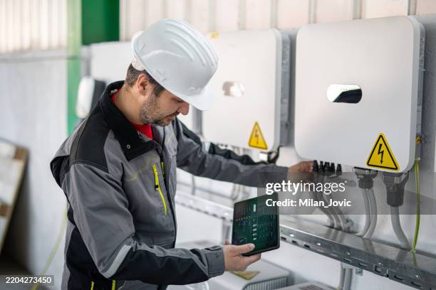 engineer using a digital tablet to examine electric smart grid system - solar panel electrician stock pictures, royalty-free photos & images