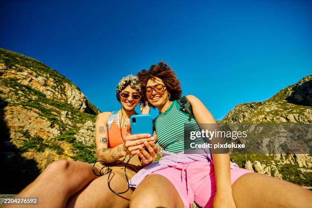 dos mujeres excursionistas de la generación z escuchando música en su teléfono inteligente - generación z fotografías e imágenes de stock