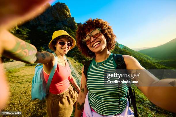 two smiling female tourists taking a selfie while hiking in the mountains - selfie stockfoto's en -beelden