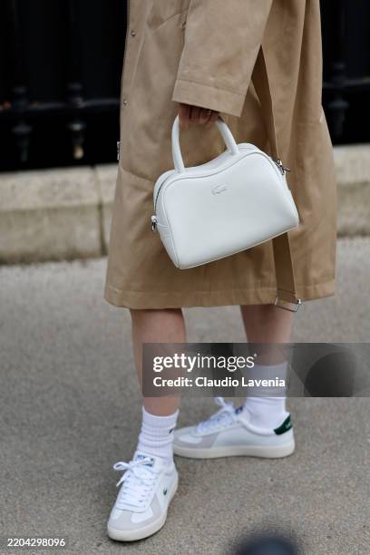 Guest wears white Lacoste bag, outside Lacoste, during the Womenswear Fall/Winter 2025/2026 as part of Paris Fashion Week on March 09, 2025 in Paris,...