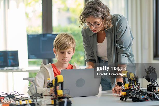 teenagers focus on computer input code to control robotic arms, enhancing problem-solving skills in a dynamic stem environment. - robot teacher stock pictures, royalty-free photos & images
