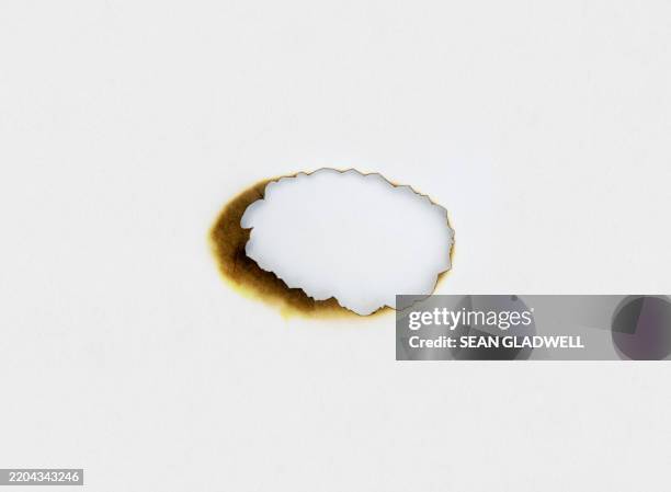 scorched burnt hole - torn hole stock pictures, royalty-free photos & images