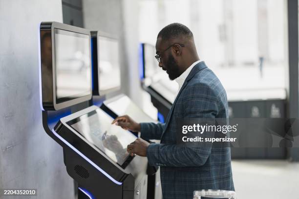 uomo professionale che utilizza il chiosco al terminal dell'aeroporto - chiosco foto e immagini stock