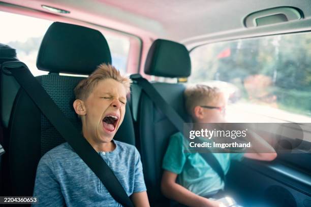 petit garçon fatigué et mignon qui bâille lors d’un long voyage en voiture ennuyeux. - grimace de crispation photos et images de collection