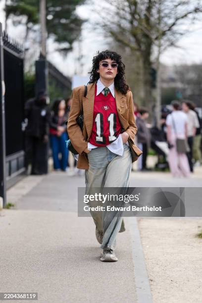 Loic Hornecker wears transparent frames black lens sunglasses, white buttoned up long sleeve shirt, dark green pattern necktie, dark red San...