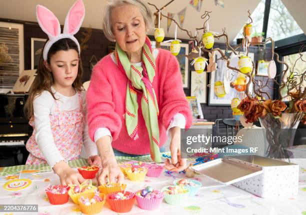 grandmother and granddaughter making easter cakes together in kitchen - easter stock pictures, royalty-free photos & images