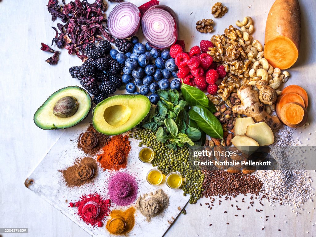 Multi colored vegetables, fruits, legumes, nuts and spices on wooden table