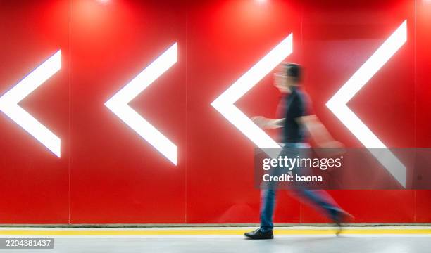man walking to the direction of the arrows in front of red wall - vision bildbanksfoton och bilder