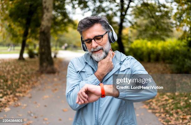 mature man checking her pulse after a run - taking pulse stock pictures, royalty-free photos & images