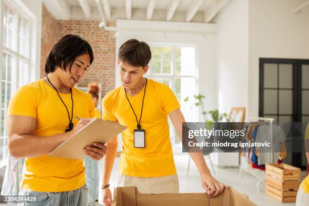 freiwillige aus der gemeinde verpacken lebensmittel für die verteilung - chancengleichheit stock-fotos und bilder