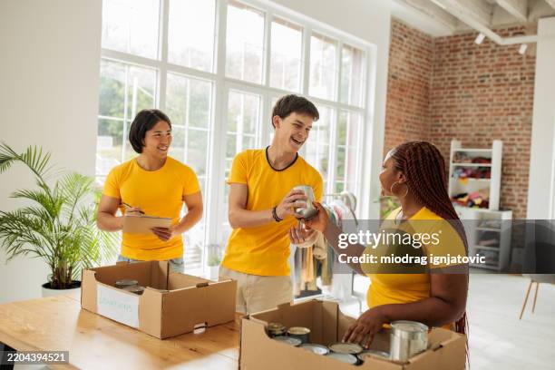 freiwillige aus der gemeinde verpacken lebensmittel für die verteilung - chancengleichheit stock-fotos und bilder