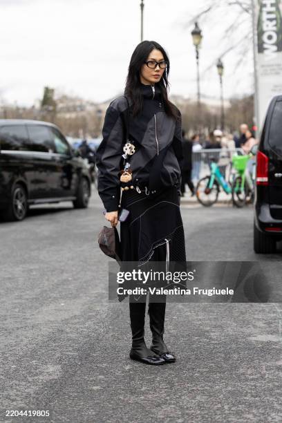 Guest wears a black and grey striped hoodie, a black midi skirt, grey long socks and black leather ballerinas outside Zimmermann show during the...