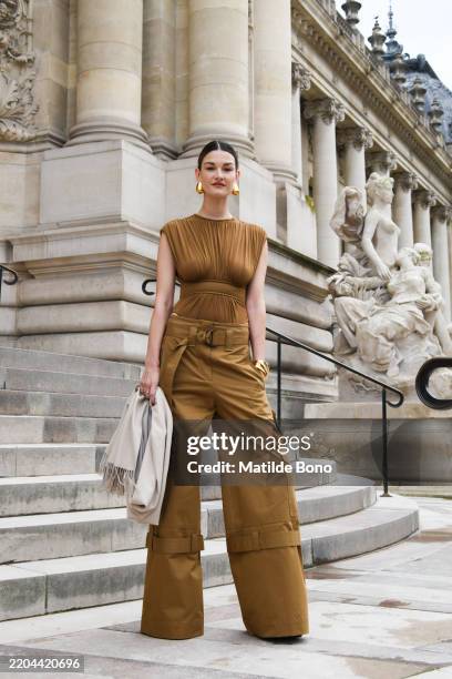 Ophelie Guillermand wears brown top, brown cargo pants, black bag, cream scarf, outside Zimmermann during the Womenswear Fall/Winter 2025/2026 as...