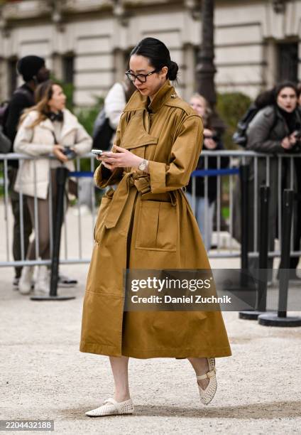 Guest is seen wearing a tan trench coat, crotchet shoes and eyewear outside the Zimmermann show during the Womenswear Fall/Winter 2025/2026 as part...