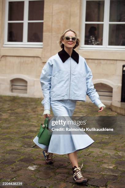 Violet Grace Atkinson wears light blue skirt, light blue jacket with black collar, green Loewe bag and brown and pale yellow sneakers outside the...