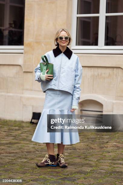 Violet Grace Atkinson wears light blue skirt, light blue jacket with black collar, green Loewe bag and brown and pale yellow sneakers outside the...