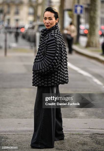 Guest is seen wearing a black textured coat, black pants outside the Rokh show during the Womenswear Fall/Winter 2025/2026 as part of Paris Fashion...