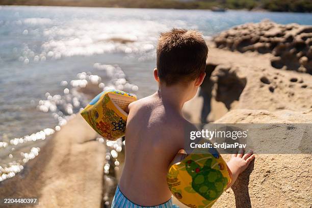 little boy on the rocky beach - water wing stock pictures, royalty-free photos & images