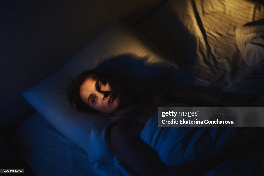 Woman Lying Awake in Bed with Dramatic Lighting