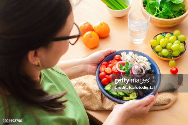mujer sosteniendo un plato de ensalada griega saludable - comida mediterránea fotografías e imágenes de stock