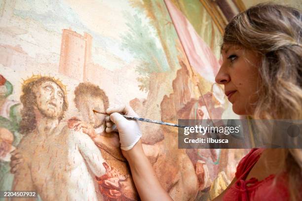 restauratore che lavora all'antico affresco della cappella all'aperto in italia: restauro pittorico dell'arte religiosa - affresco foto e immagini stock