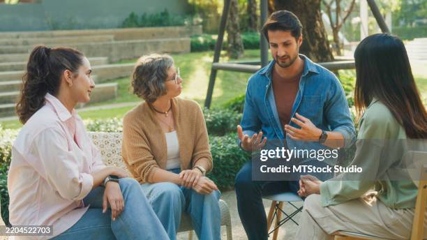 diverse group people engaging in supportive group therapy session, sharing personal stories and advice to promote mental health and recovery in park. mental health community concept. - contar histórias imagens e fotografias de stock