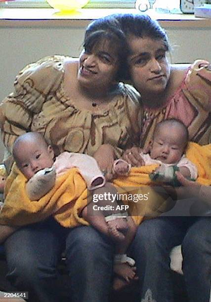 This undated picture shows four-month old South Korean twin girls Min Sa-Rang and Min Ji-Hye being held by Iranian twins Ladan and Laleh Bijani at...