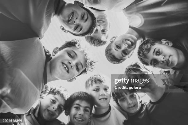 squadra di calcio del ragazzo in piedi in cerchio e guardando in basso verso la macchina fotografica - solo bambini maschi foto e immagini stock