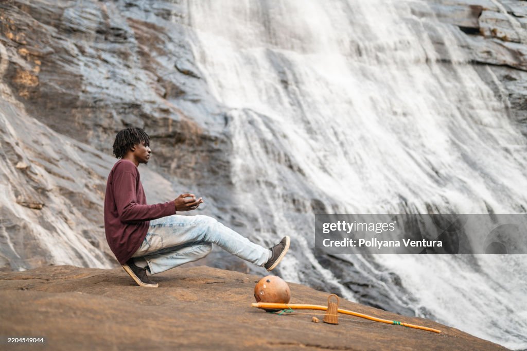 Afro man dancing capoeira at the waterfall