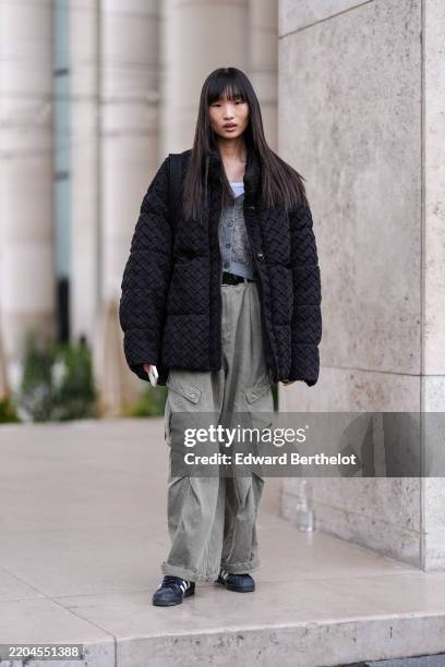 Guest wears white tank top, light gray pattern cardigan sweater, black woven oversized puffer jacket, light green cargo denim jean baggy pants, black...