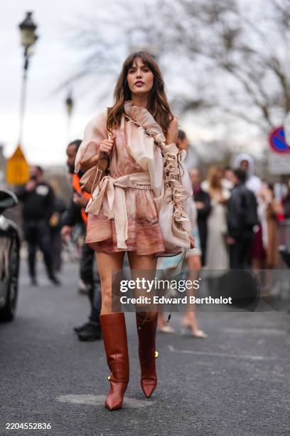 Ruby Sear wears light pink sheer mesh pattern asymmetrical belted Zimmerman mini dress, light brown Zimmermann leather bag, shiny dark brown pointed...