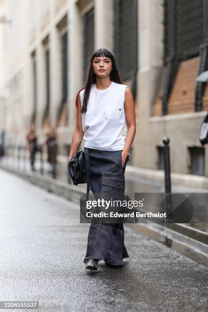 Clara Kong Villa wears dark brown bangs with long burgundy bordeaux hair stripes, white sleeveless t-shirt, navy blue cargo black sheer mesh maxi...