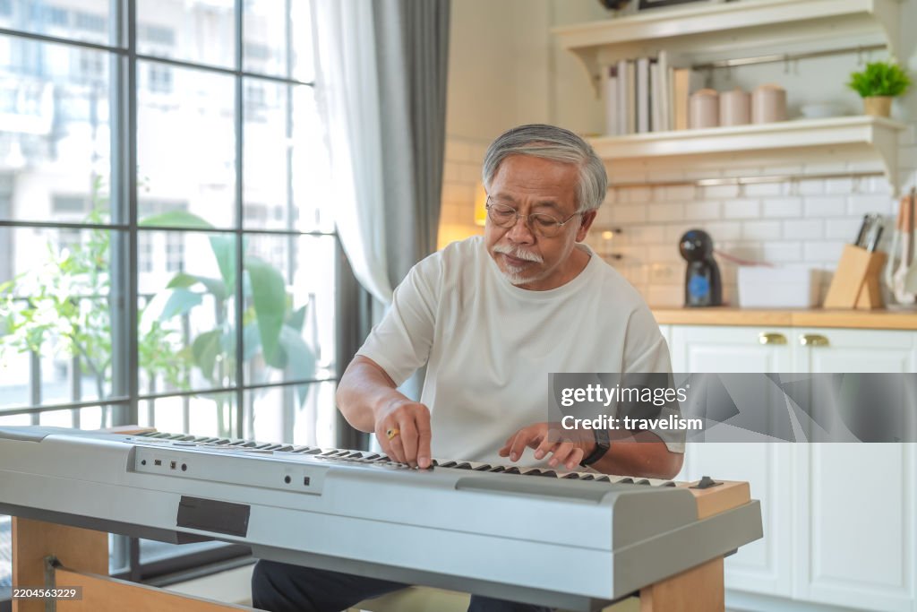 Happiness cheerful Senior man playing piano to relax at home on vacation old man play piano, having fun and enjoying time alone