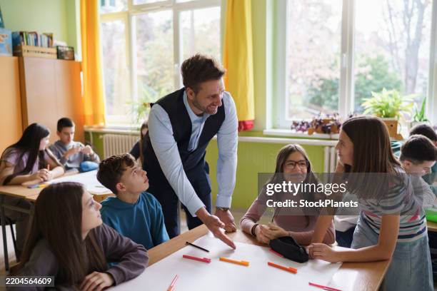 a teacher talks to children while they are doing a school project - junior high stock pictures, royalty-free photos & images