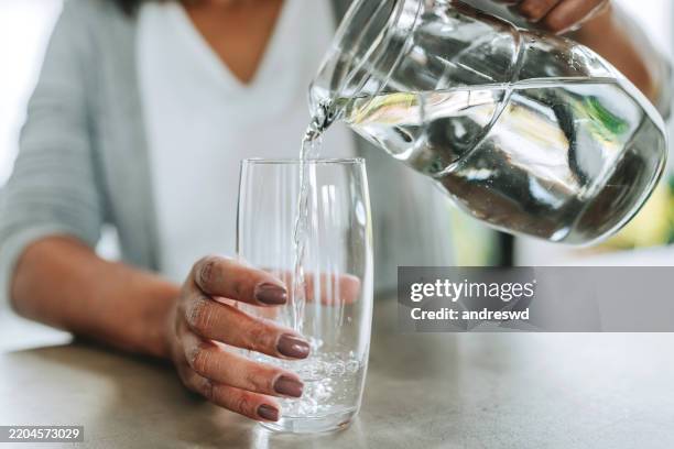 woman pouring cup water on glass - woman drinking glass stock pictures, royalty-free photos & images