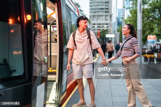 hispanic couple boarding sydney tram holding hands smiling - tram stock pictures, royalty-free photos & images