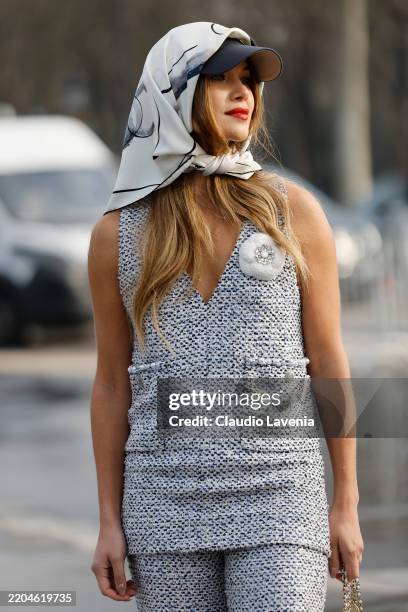 Guest wears white and blue tweed top with matching pants, black hat, white printed silk hair scarf, outside Chanel, during the Womenswear Fall/Winter...