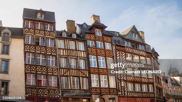 low angle view of the multicolor red, yellow and brown traditional half-timbered facades of the leaned 17th century houses of the place du champ-jacquet, a famous square in rennes, iile-et-vilaine - brittany (bretagne) - western france. - iile et vilaine stock pictures, royalty-free photos & images