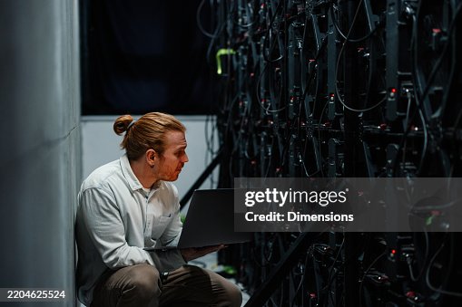 Technician using laptop checking big data servers in data center Technician using laptop checking big data servers in data center